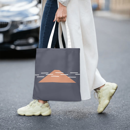 Person walking on a street holding a tote bag with a design on it.