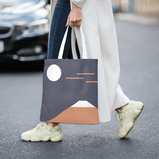 Person walking on a street holding a tote bag with a mountain design.