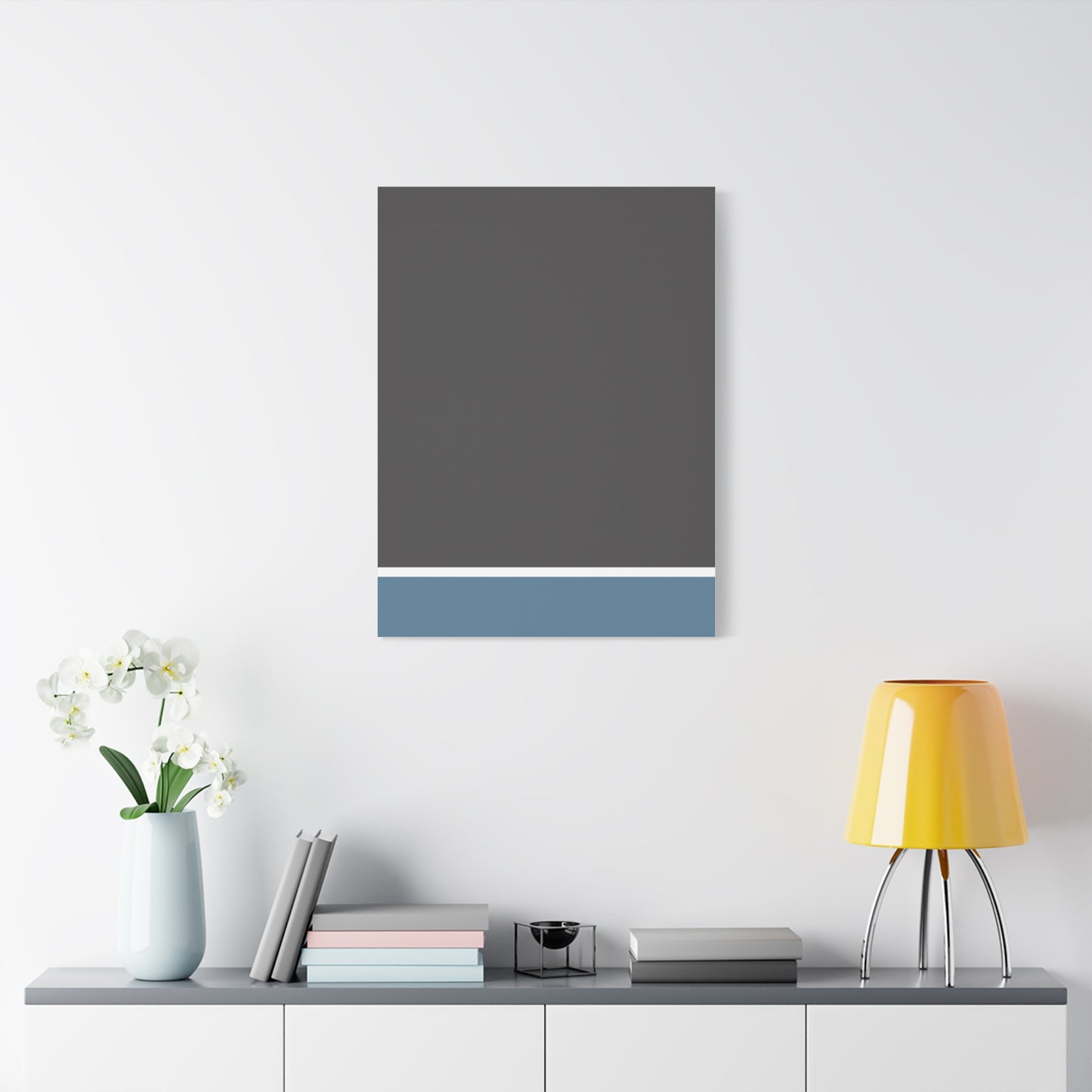 Gray and blue abstract painting on a white wall above a shelf with decor items.