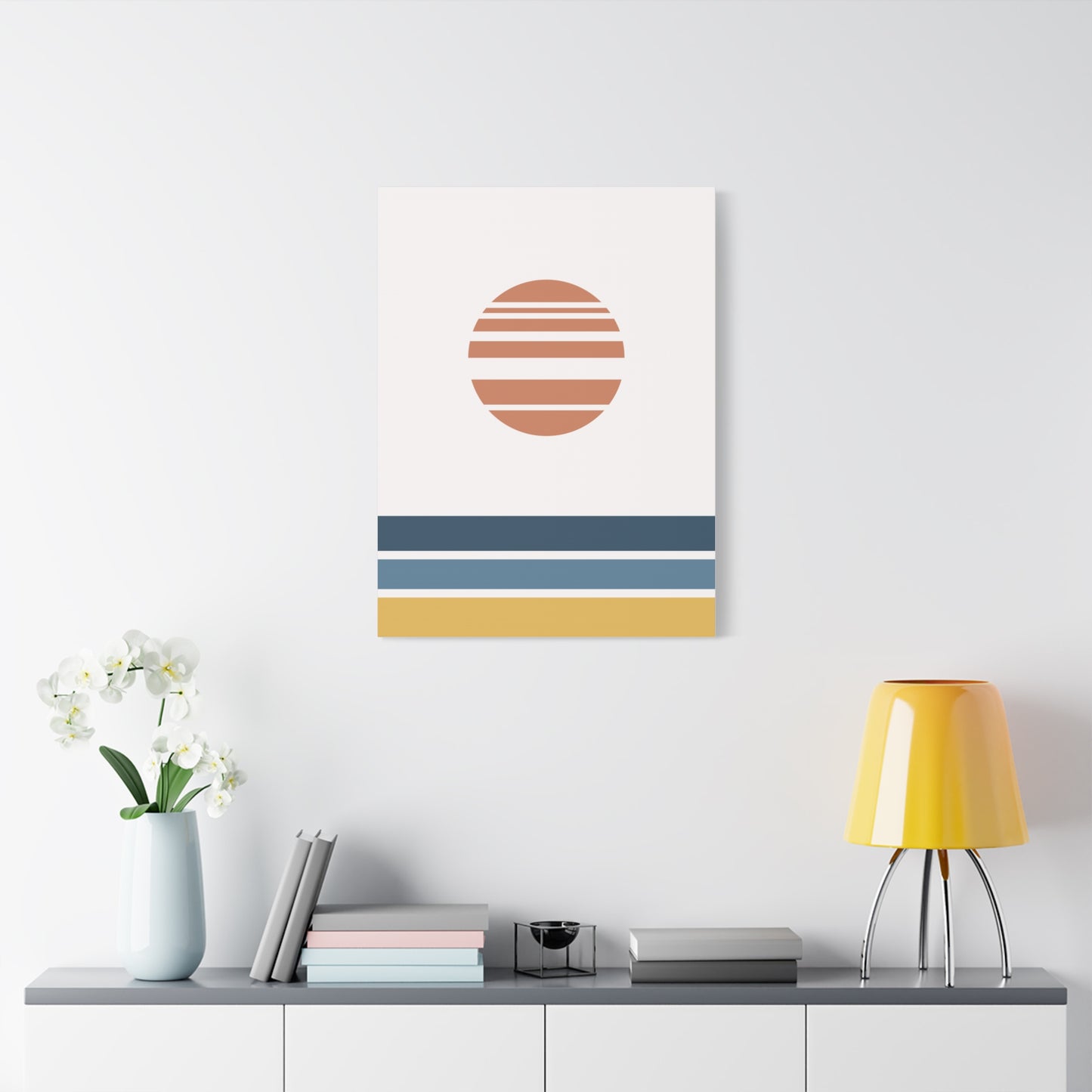 Modern interior design with a wall art piece featuring a sun and horizontal stripes, a yellow lamp, and books on a shelf.