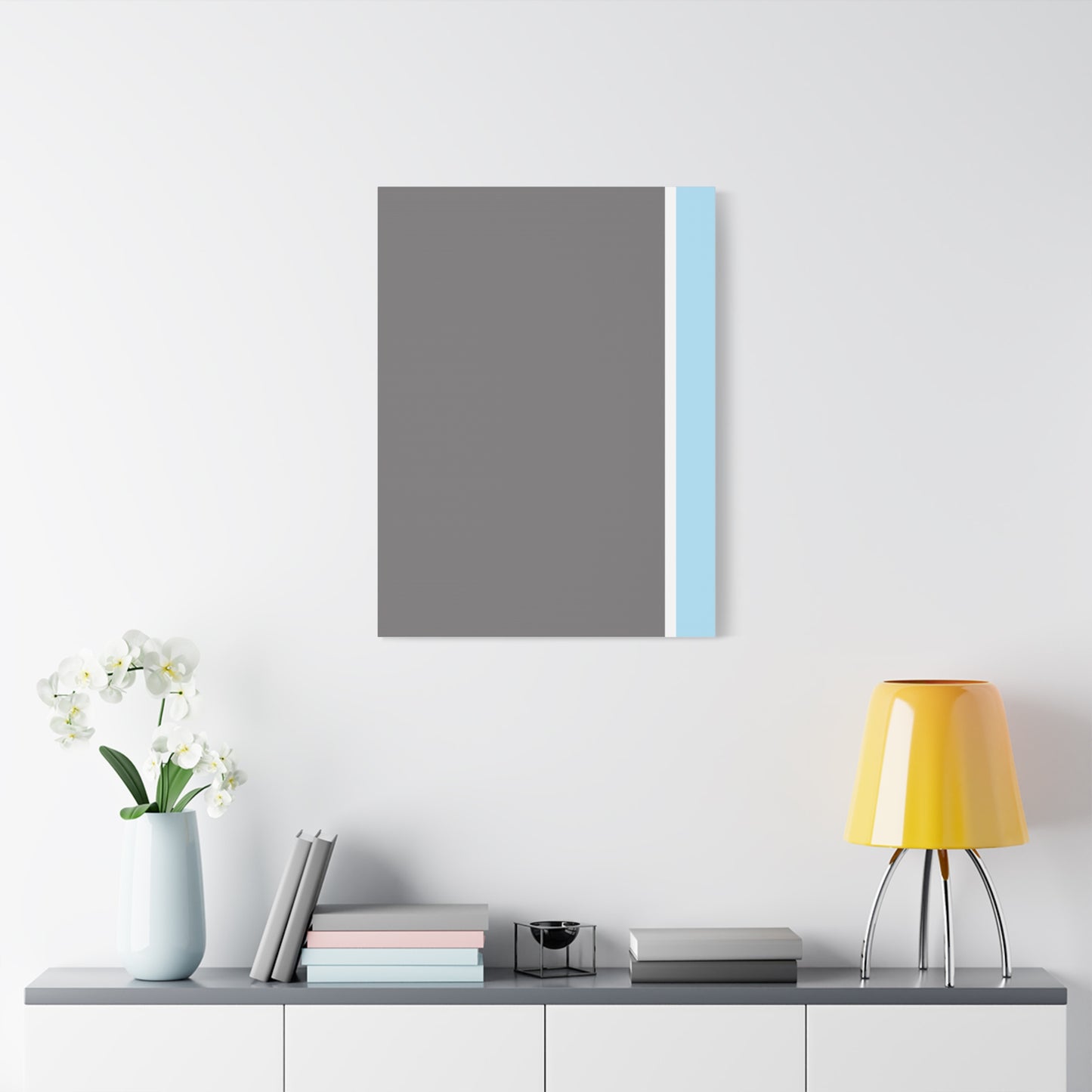 Modern interior design with a gray and blue abstract painting, yellow lamp, and books on a shelf.