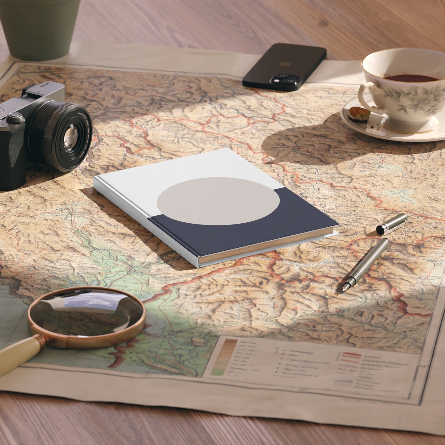 Notebook, camera, magnifying glass, and tea cup on a map