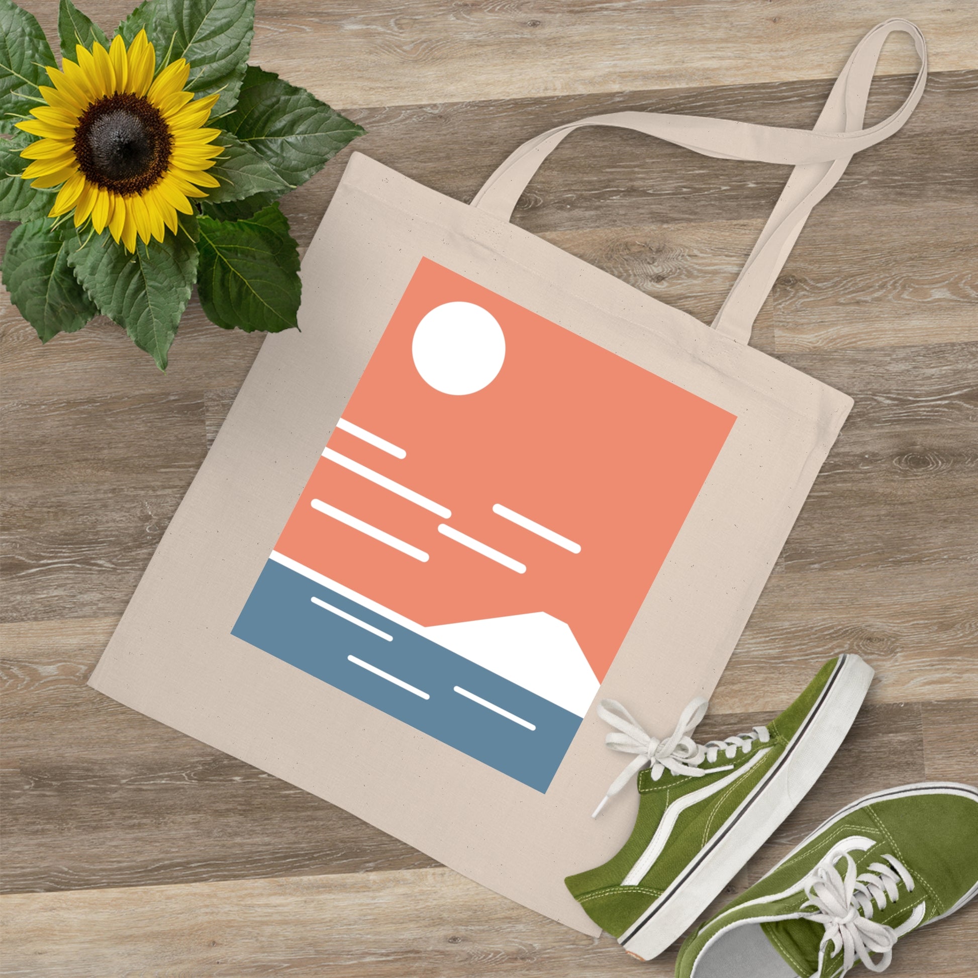 Beige tote bag with a colorful design, green sneakers, and a sunflower on a wooden surface.