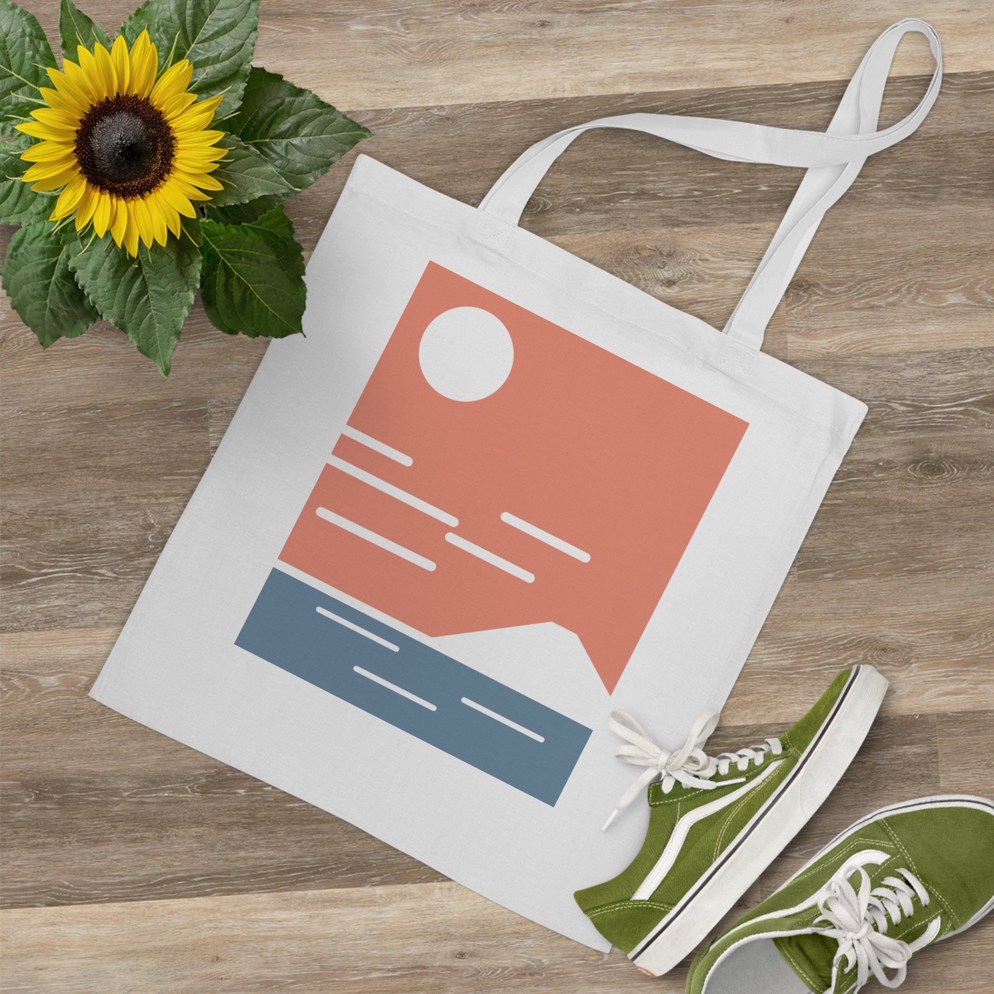 Tote bag with a design, green sneakers, and sunflower on a wooden surface