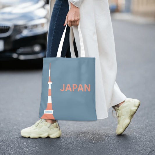 Person holding a tote bag with a Tokyo Tower design and 'Japan' text on a street.