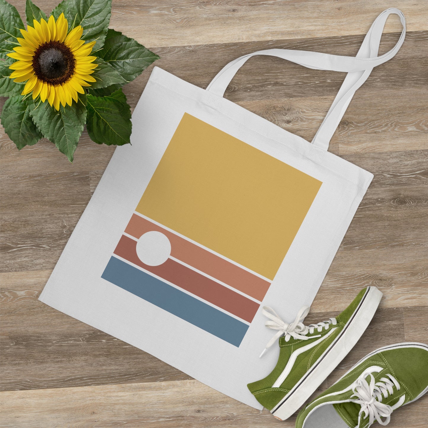 Tote bag with geometric design, green sneakers, and sunflower on wooden surface