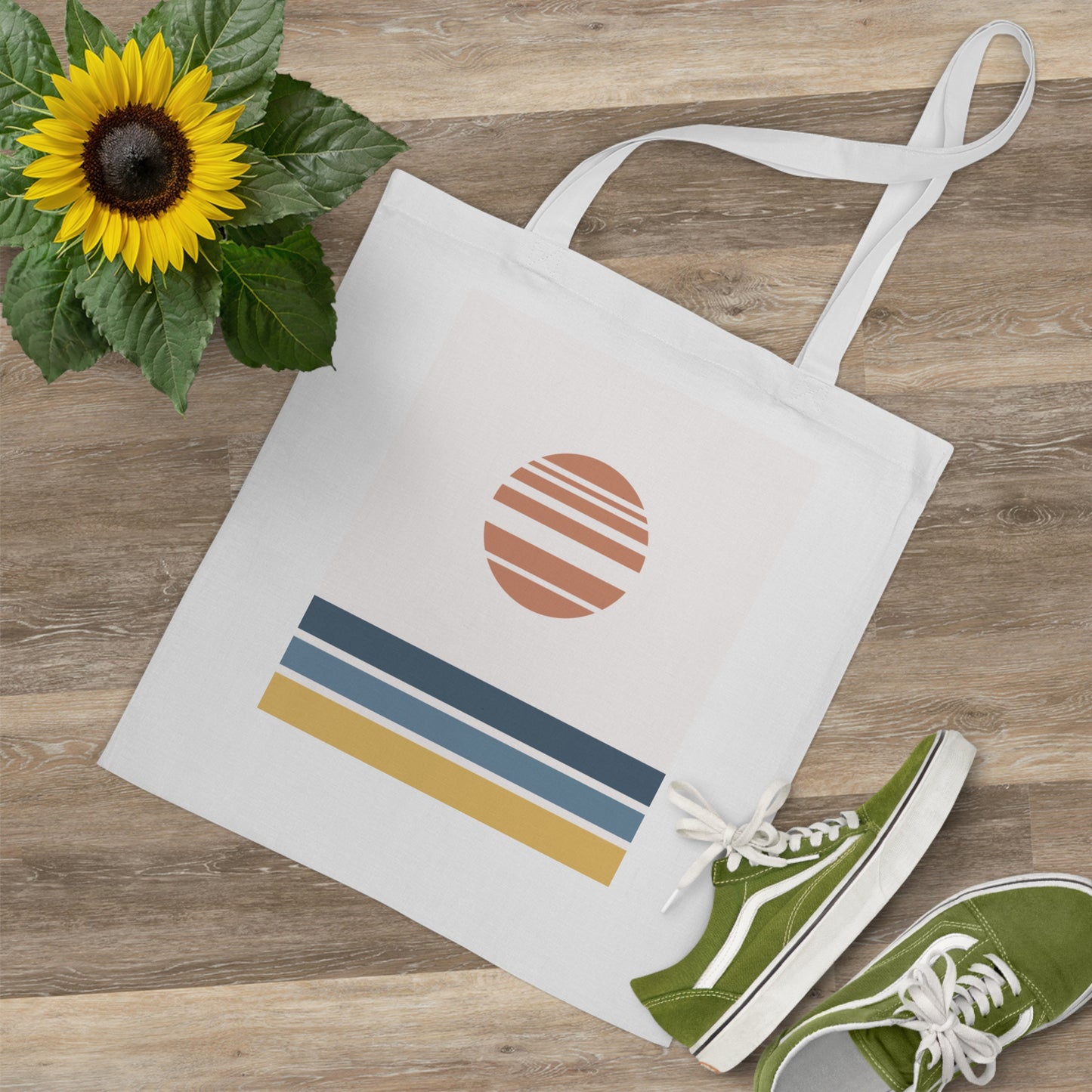 Tote bag with sun design, green sneakers, and sunflower on a wooden surface
