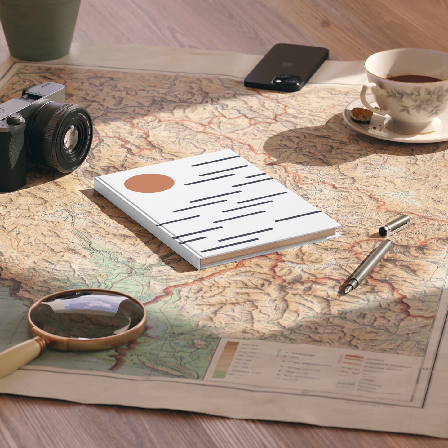 Notebook, camera, magnifying glass, and tea cup on a map