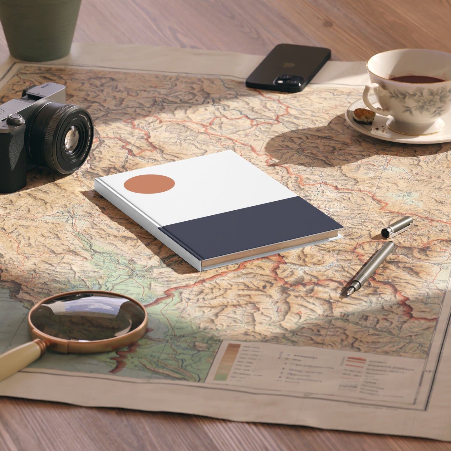 Notebook, camera, magnifying glass, and tea cup on a map