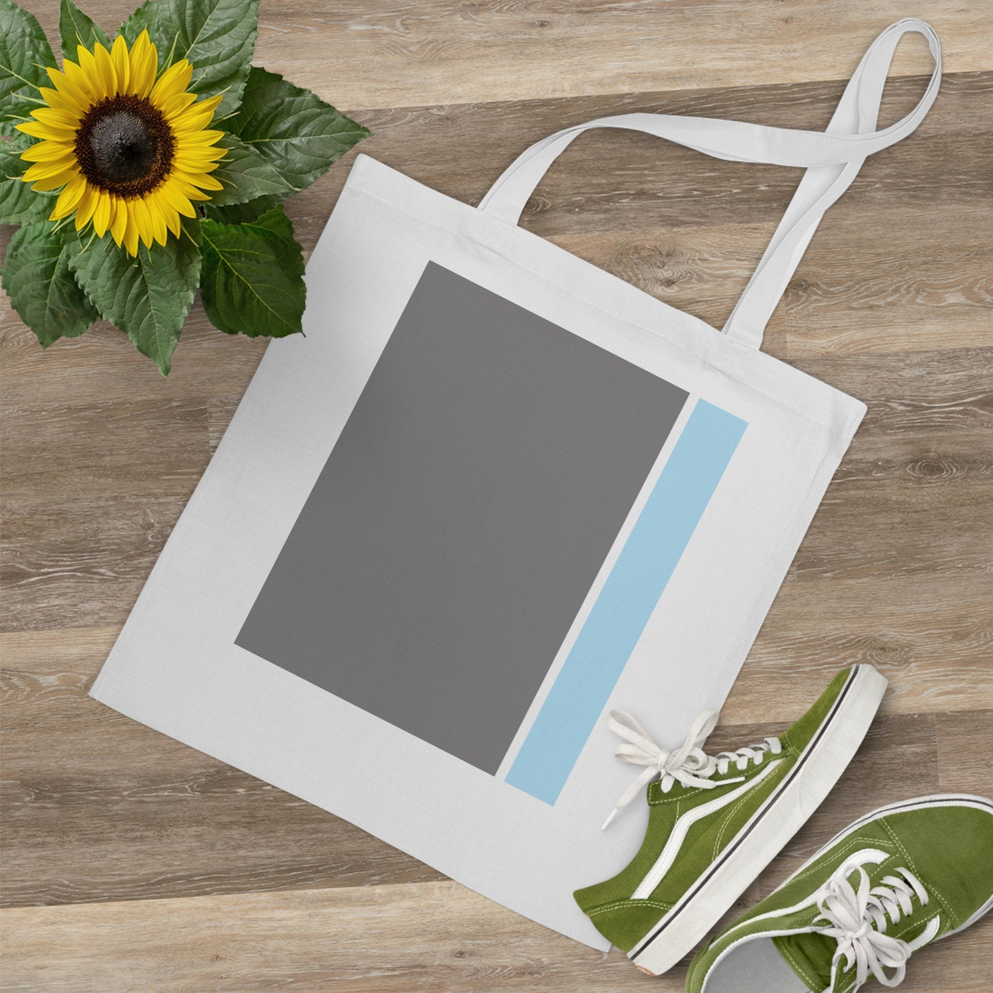 Tote bag with a sunflower and green sneakers on a wooden surface