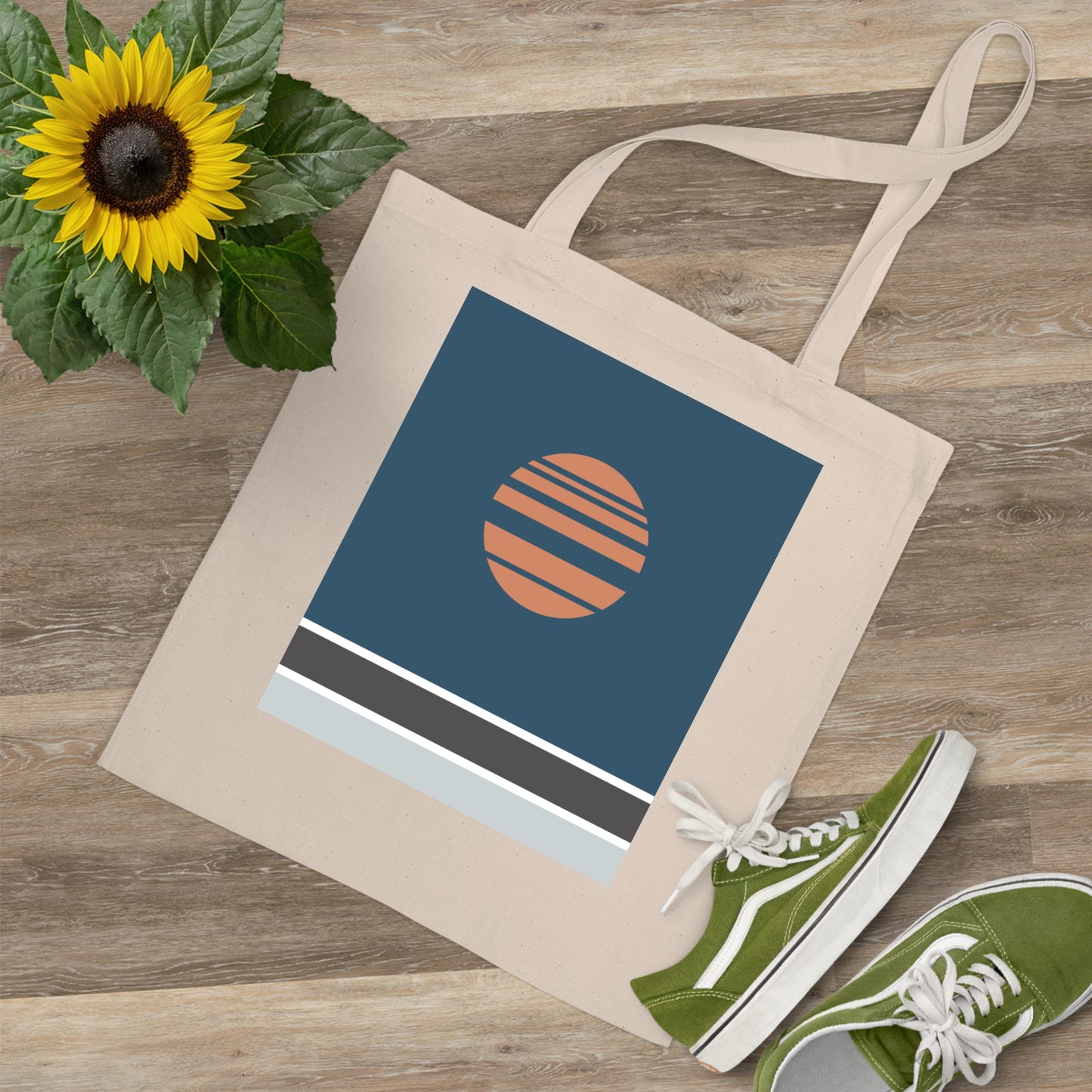 Tote bag with a sun design, green sneakers, and a sunflower on a wooden surface