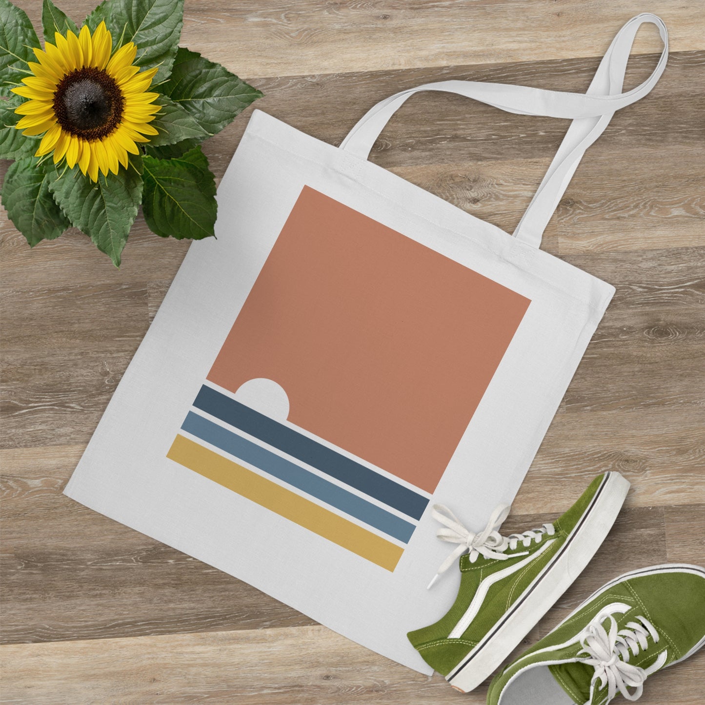 Tote bag with geometric design, green sneakers, and sunflower on wooden surface
