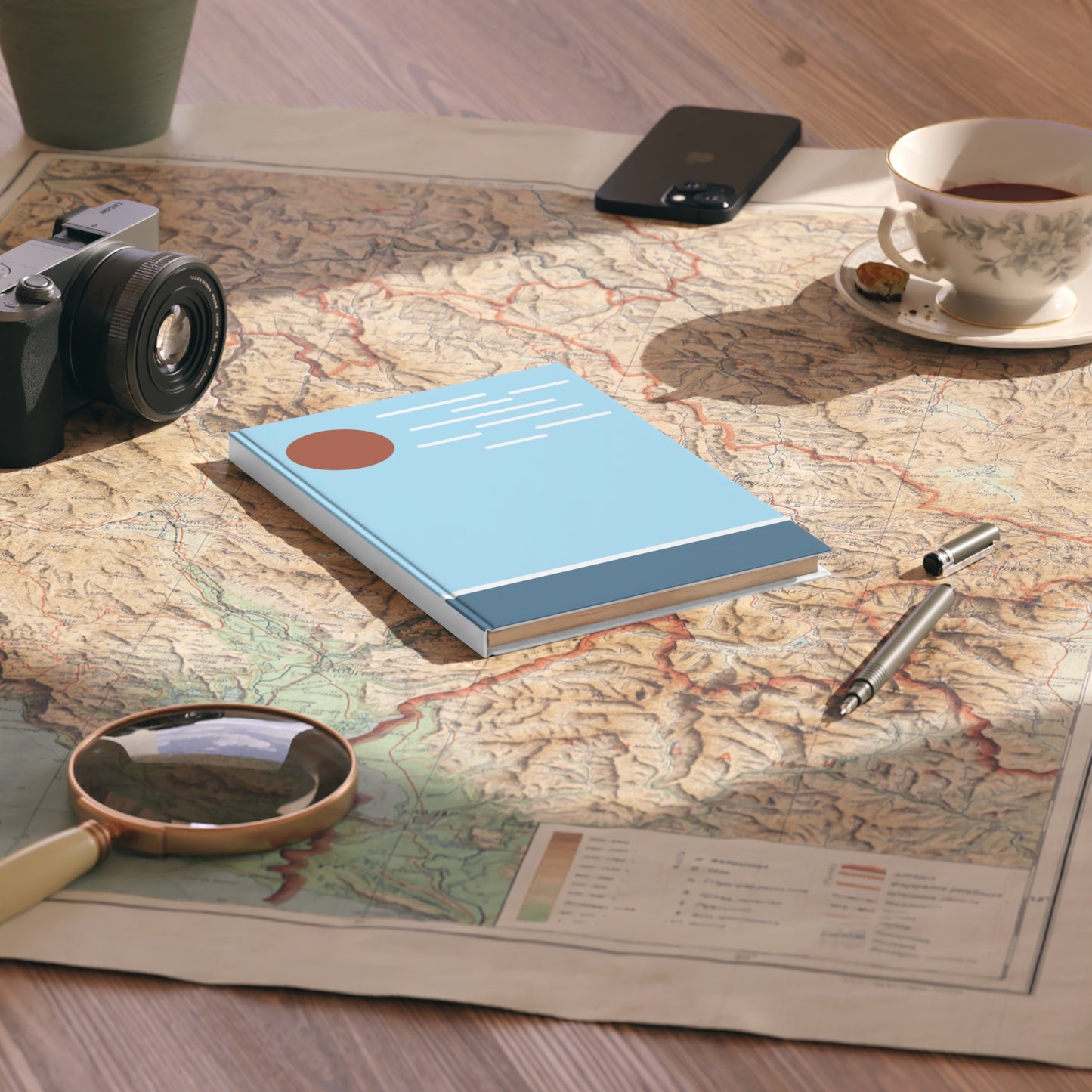 Notebook, camera, magnifying glass, and tea cup on a map
