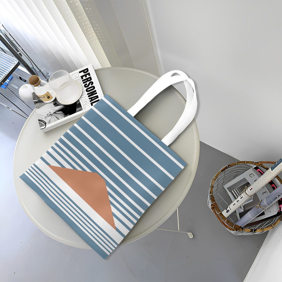 Tote bag with blue and white stripes and a brown abstract design on a round table.