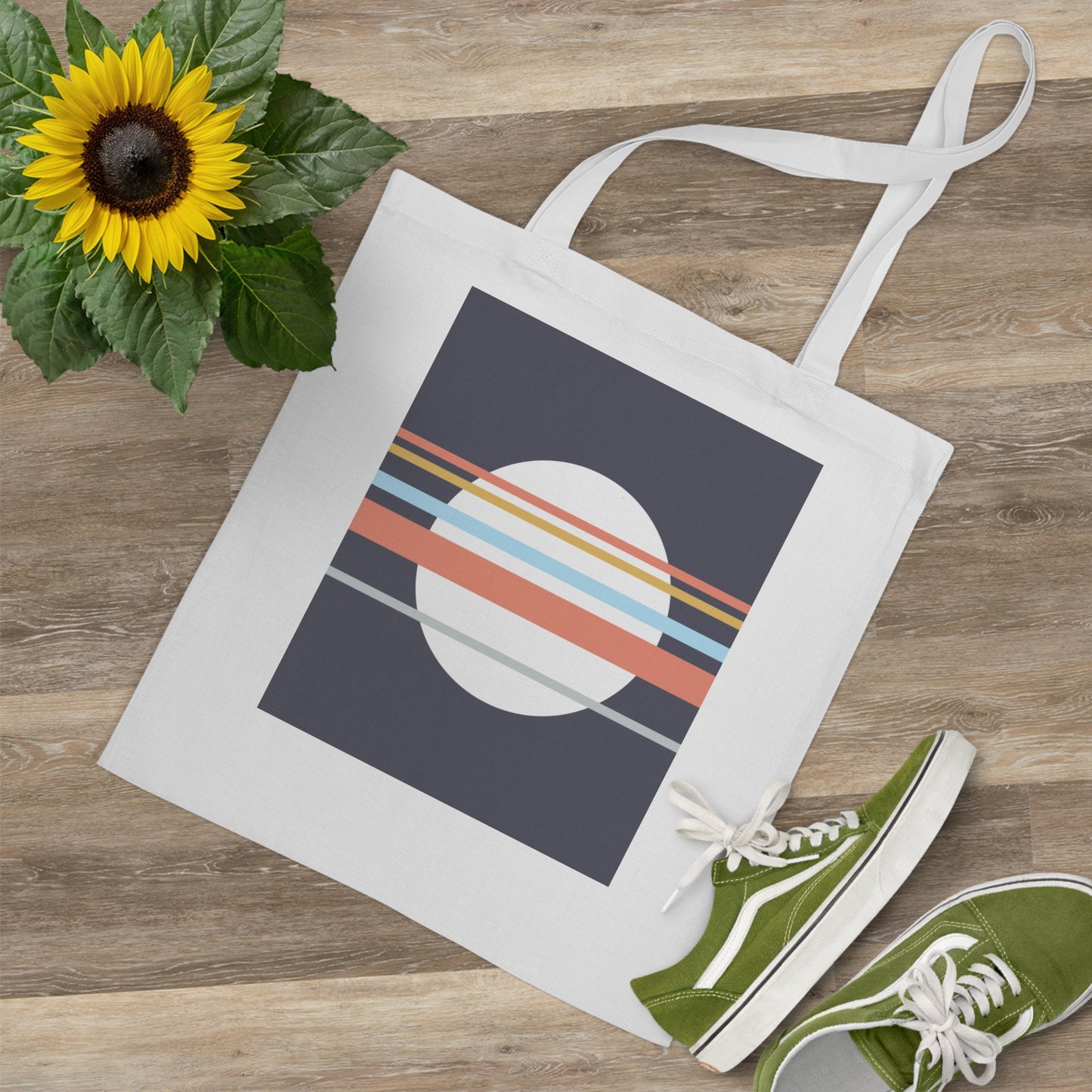 Tote bag with geometric design, green sneakers, and sunflower on wooden surface