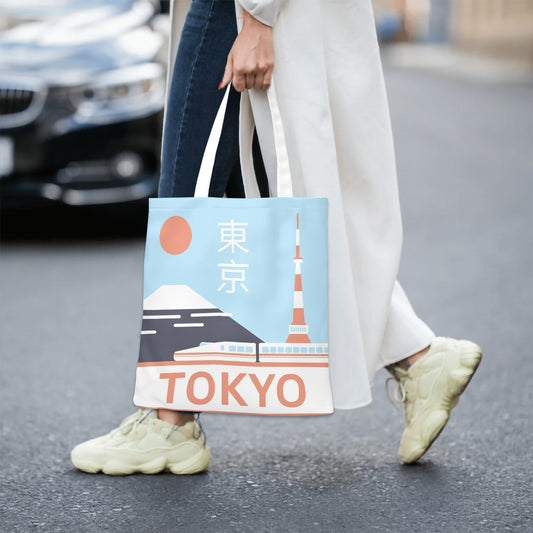Person holding a tote bag with Tokyo design on a street.