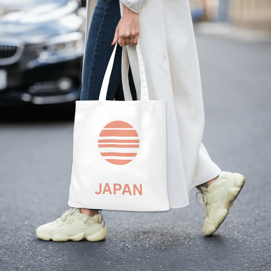 Person holding a tote bag with 'Japan' and a sun design on a street.