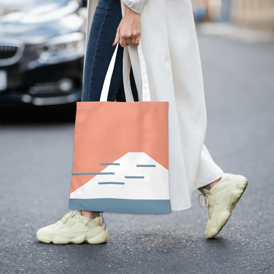Person holding a tote bag with a mountain design on a street.