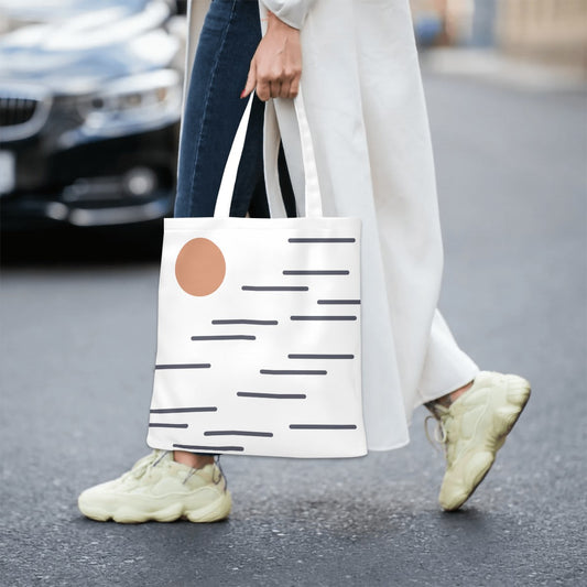 Person walking on a street holding a white tote bag with a brown circle design.