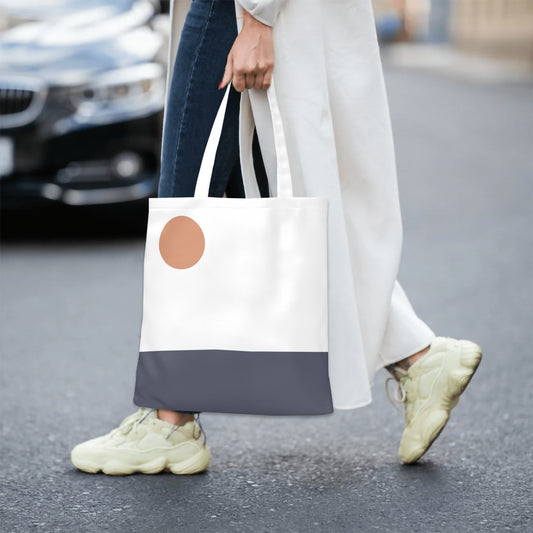 Person holding a tote bag with a round brown patch on a street.