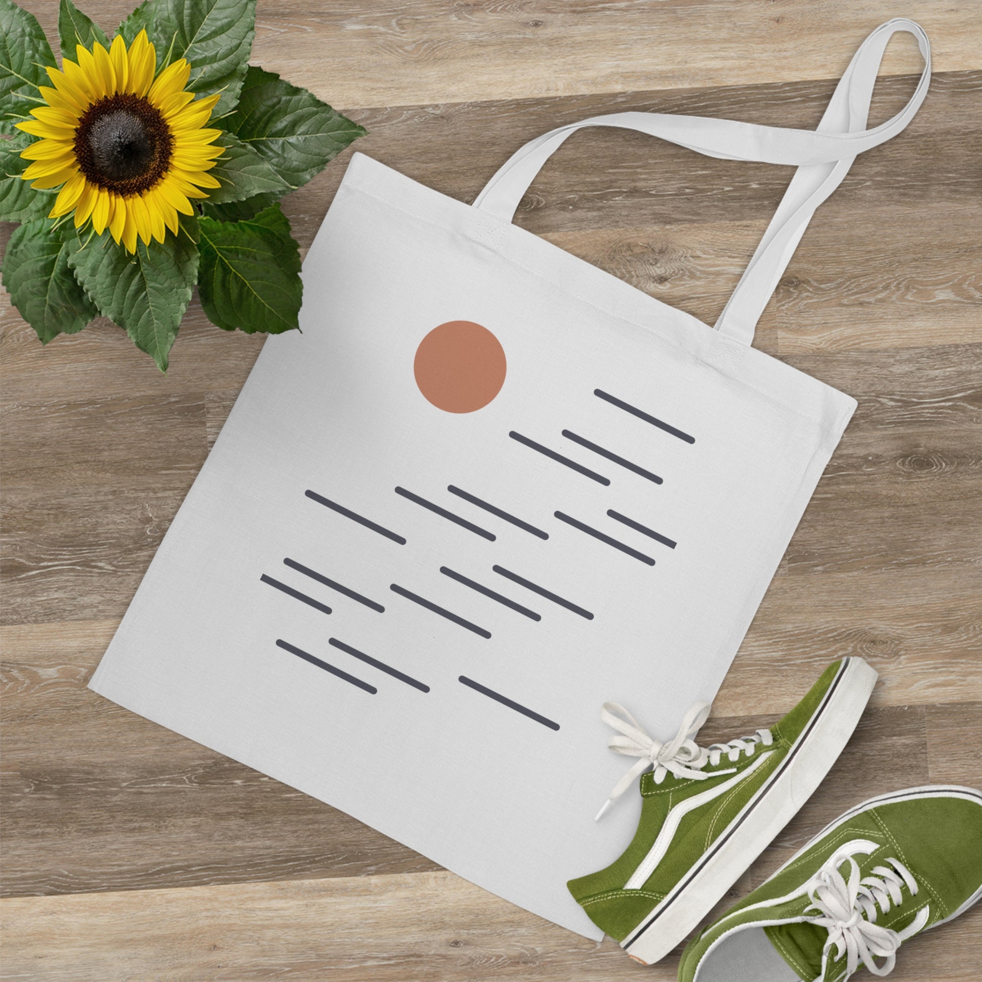 Tote bag with floral design, sunflower, and green sneakers on a wooden surface