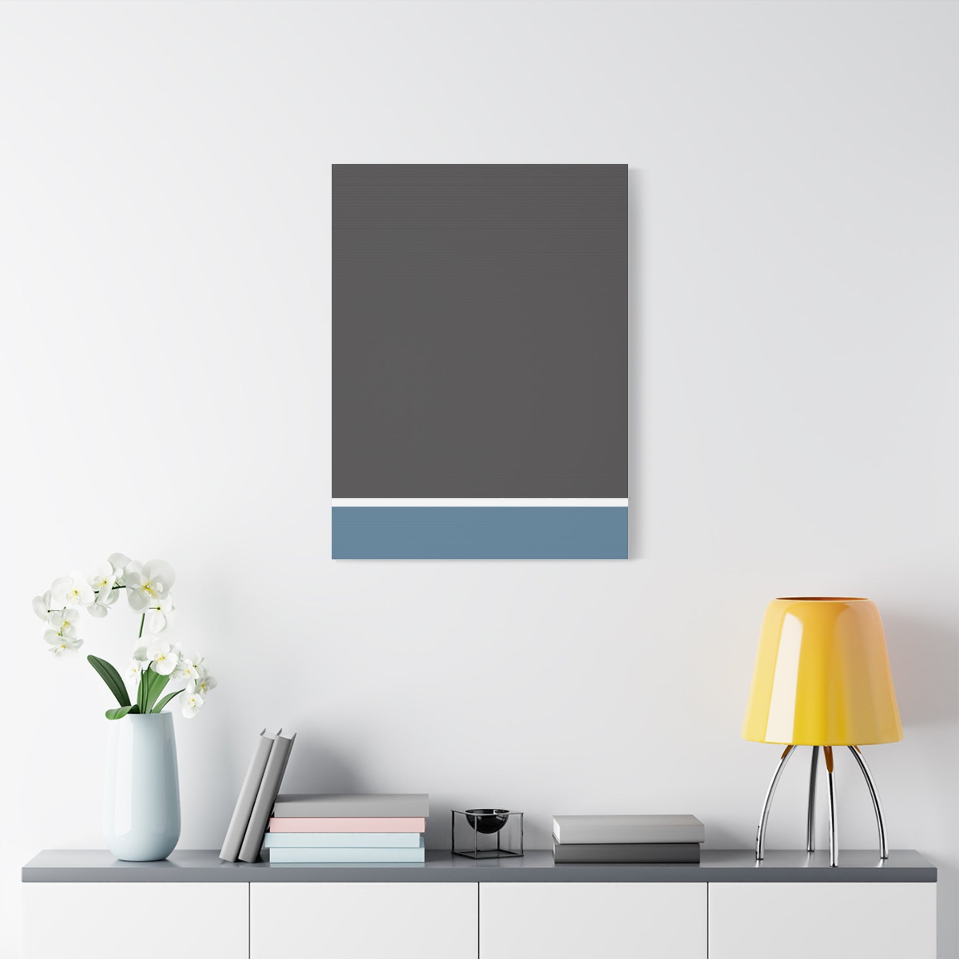 Gray and blue abstract painting on a white wall above a shelf with decor items.