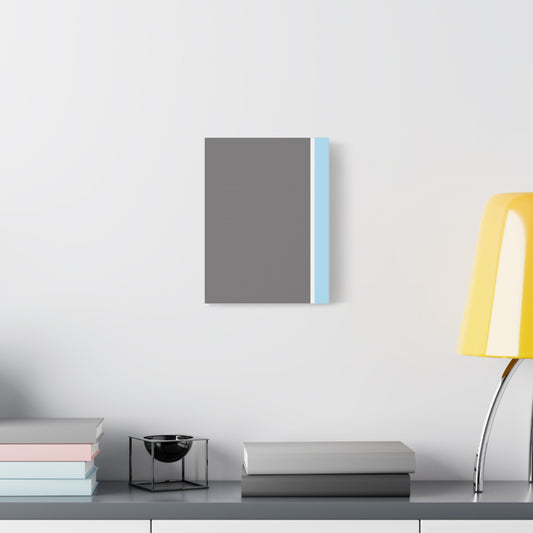 Gray and blue rectangular object on a white wall with books and a lamp on a table below.