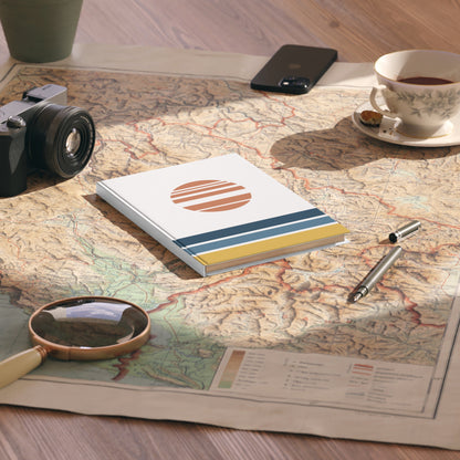 Notebook with a sun design on a map with a camera, phone, cup, and pen.