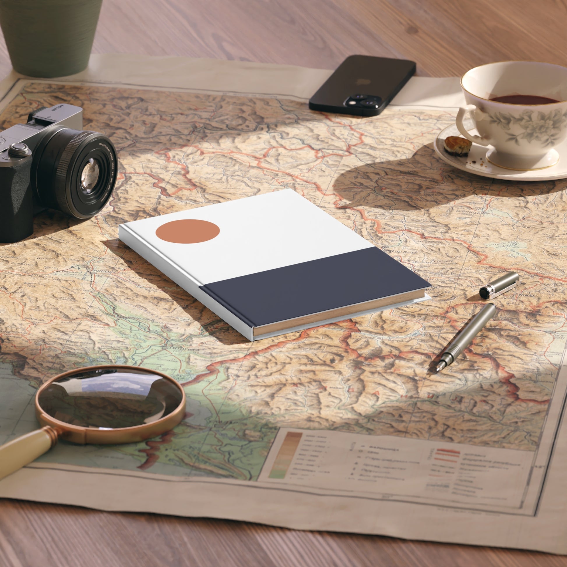 Notebook, camera, magnifying glass, and tea cup on a map