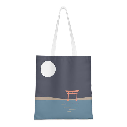 A canvas tote bag with white shoulder straps, featuring a minimalist graphic print of a Japanese torii gate at night under a large white moon over blue water.