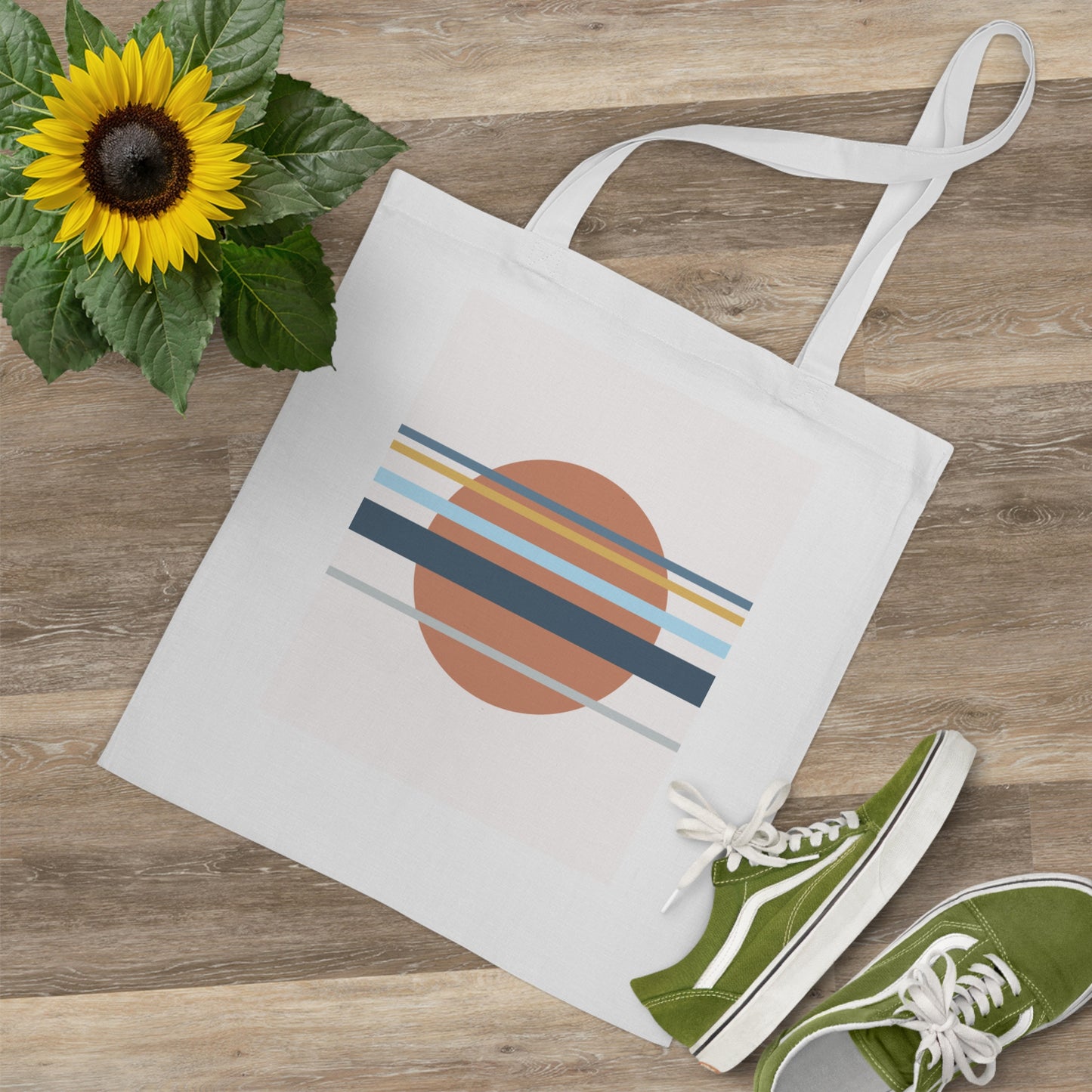 White tote bag with geometric design, green sneakers, and sunflower on wooden surface