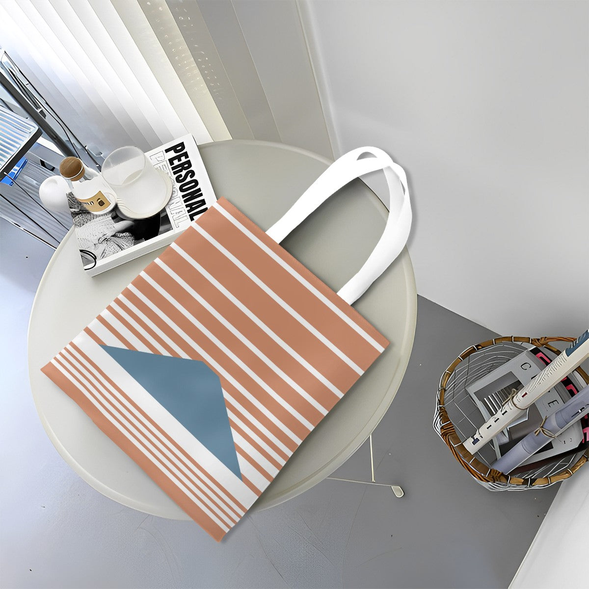 Striped tote bag on a round table with a magazine and small items.