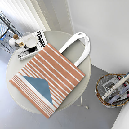 Striped tote bag on a round table with a magazine and small items.