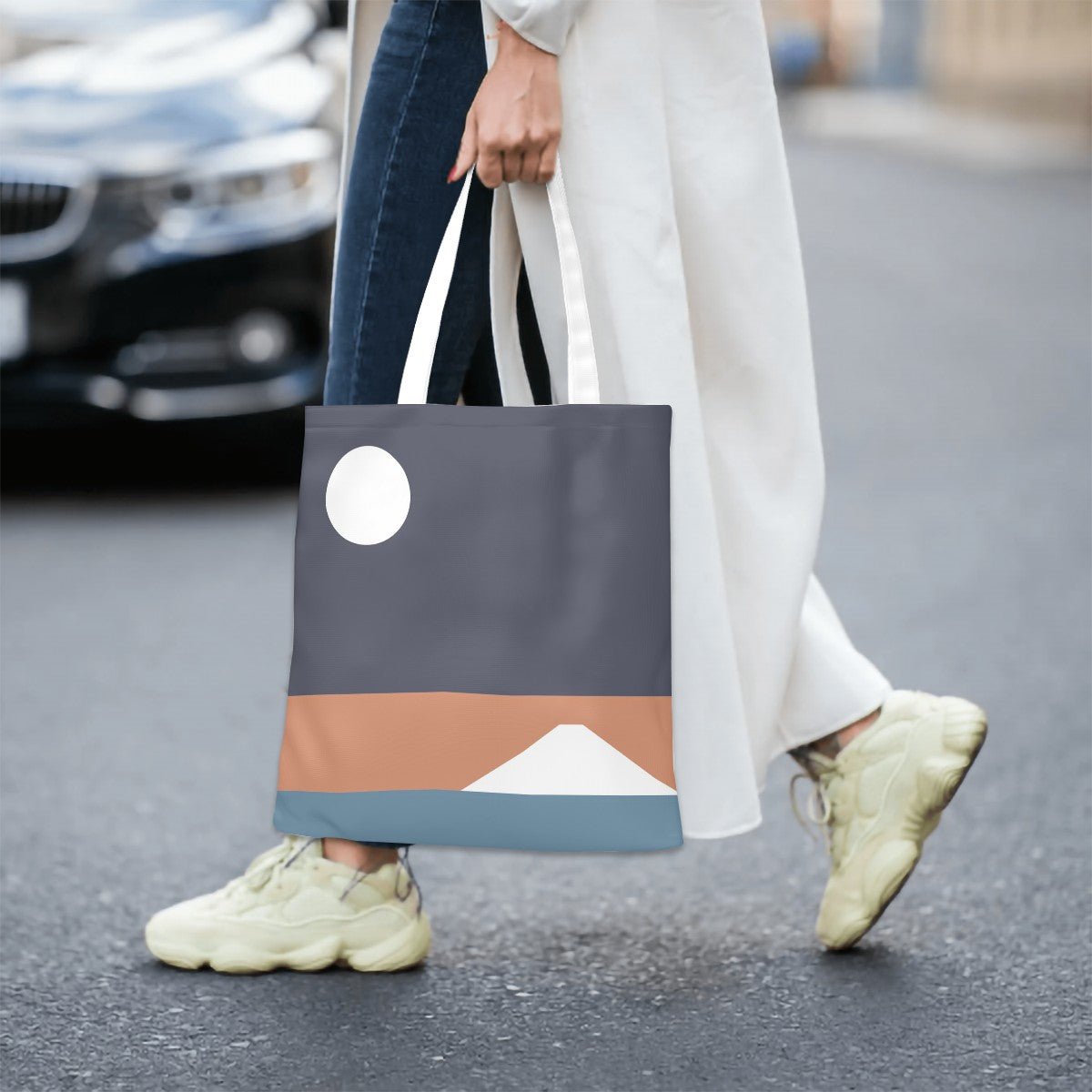 Person holding a tote bag with mountain design on a street