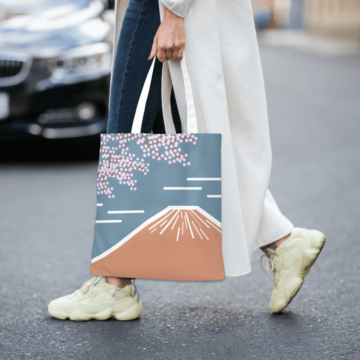 Person holding a minimalist Japanese tote bag with Mount Fuji design on a city street.